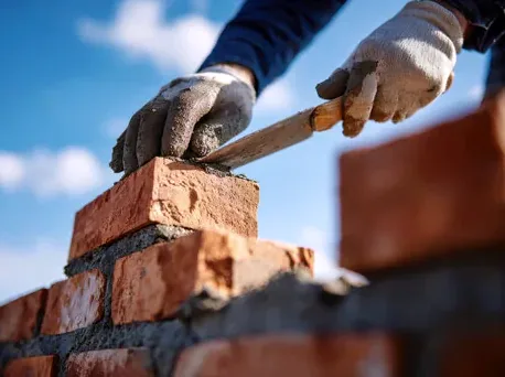 Mason laying brick to rebuild a garden wall in Summit